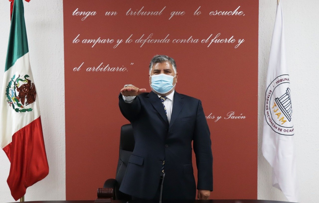 Jesus Sierra tomando protesta con la bandera nacional mexicana por un lado y con la mano al frente protestando