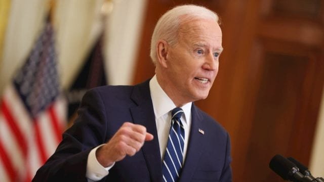 Joe Biden presidente de estados unidos discursando con la bandera de estrellas y rayas detrás de él