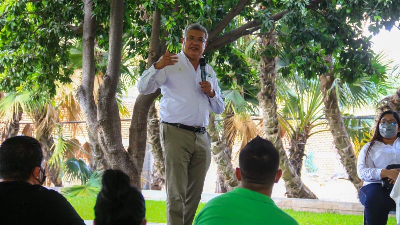 Magaña de la mora discursa frente a un auditorio con una carpa y detras se ven palmeras